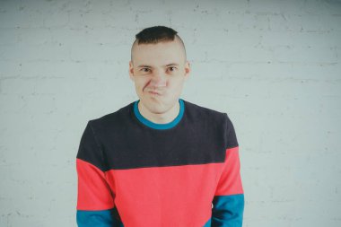 Yakışıklı olan bir tuğla duvara poz. Çizgili kazağı deli adam