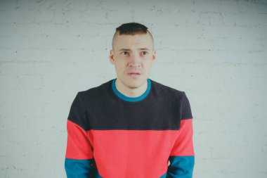 Yakışıklı olan bir tuğla duvara poz. Çizgili kazağı deli adam