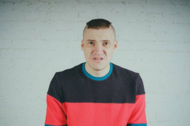 Yakışıklı olan bir tuğla duvara poz. Çizgili kazağı deli adam