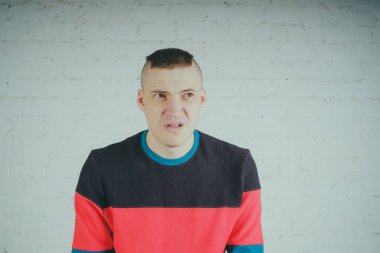 Yakışıklı olan bir tuğla duvara poz. Çizgili kazağı deli adam