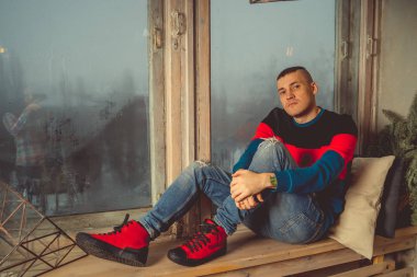 Moda yakışıklı adam bir dinlenme sahiptir, pencere kenarında oturuyor