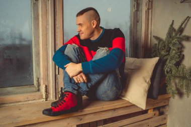 Moda yakışıklı adam bir dinlenme sahiptir, pencere kenarında oturuyor