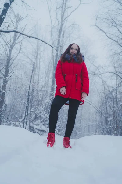 Girl in a red jacket walking in the woods. Concept: a walk in the fresh winter air