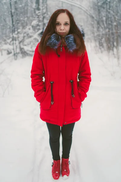 Girl in a red jacket walking in the woods. Concept: a walk in the fresh winter air