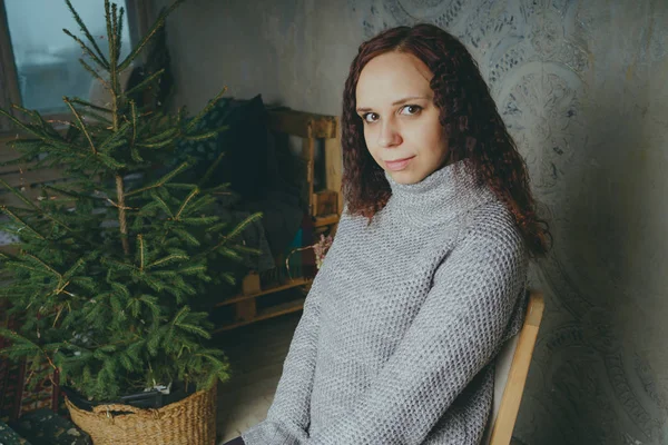 Gri bir duvara poz bir kazak bir genç kız. Sıcak kazak giymiş kadın sokak stil giyim. Temiz cilt, uzun saç