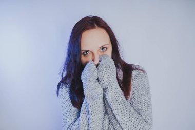 Gri bir duvara poz bir kazak bir genç kız. Sıcak kazak giymiş kadın sokak stil giyim. Temiz cilt, uzun saç