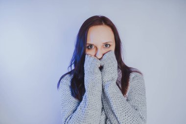 Gri bir duvara poz bir kazak bir genç kız. Sıcak kazak giymiş kadın sokak stil giyim. Temiz cilt, uzun saç