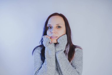 Gri bir duvara poz bir kazak bir genç kız. Sıcak kazak giymiş kadın sokak stil giyim. Temiz cilt, uzun saç