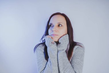 Gri bir duvara poz bir kazak bir genç kız. Sıcak kazak giymiş kadın sokak stil giyim. Temiz cilt, uzun saç