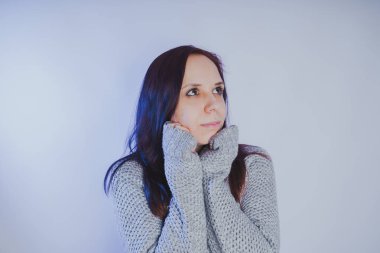 Gri bir duvara poz bir kazak bir genç kız. Sıcak kazak giymiş kadın sokak stil giyim. Temiz cilt, uzun saç