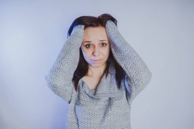 Gri bir duvara poz bir kazak bir genç kız. Sıcak kazak giymiş kadın sokak stil giyim. Temiz cilt, uzun saç