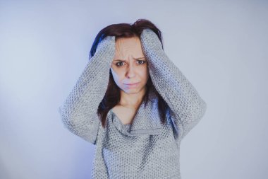 Gri bir duvara poz bir kazak bir genç kız. Sıcak kazak giymiş kadın sokak stil giyim. Temiz cilt, uzun saç