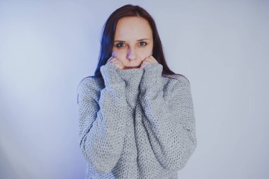 Gri bir duvara poz bir kazak bir genç kız. Sıcak kazak giymiş kadın sokak stil giyim. Temiz cilt, uzun saç