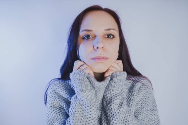 Gri bir duvara poz bir kazak bir genç kız. Sıcak kazak giymiş kadın sokak stil giyim. Temiz cilt, uzun saç