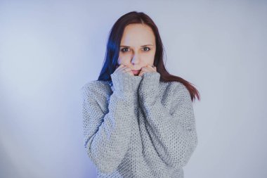 Gri bir duvara poz bir kazak bir genç kız. Sıcak kazak giymiş kadın sokak stil giyim. Temiz cilt, uzun saç