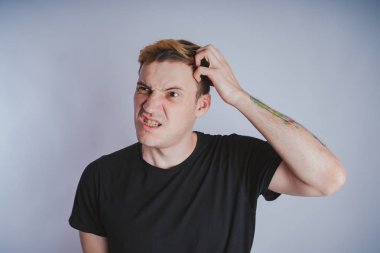 Stüdyoda poz ile genç bir adam. Kısa saç ve temiz cilt. Duygusal portre. Sokak tarzı giyim: siyah t-shirt ve kot pantolon