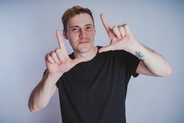 Stüdyoda poz ile genç bir adam. Kısa saç ve temiz cilt. Duygusal portre. Sokak tarzı giyim: siyah t-shirt ve kot pantolon