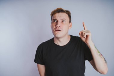 Stüdyoda poz ile genç bir adam. Kısa saç ve temiz cilt. Duygusal portre. Sokak tarzı giyim: siyah t-shirt ve kot pantolon