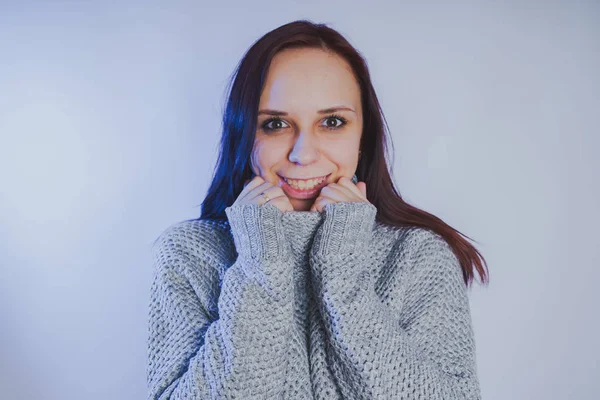 Gri bir duvara poz bir kazak bir genç kız. Sıcak kazak giymiş kadın sokak stil giyim. Temiz cilt, uzun saç