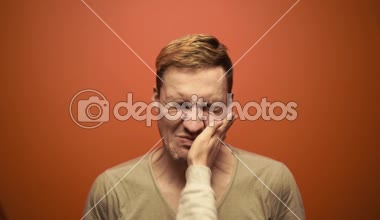 Turuncu arka planda tokat yiyen bir adam. Turuncu arka planda duran mutsuz, korkmuş bir adam.