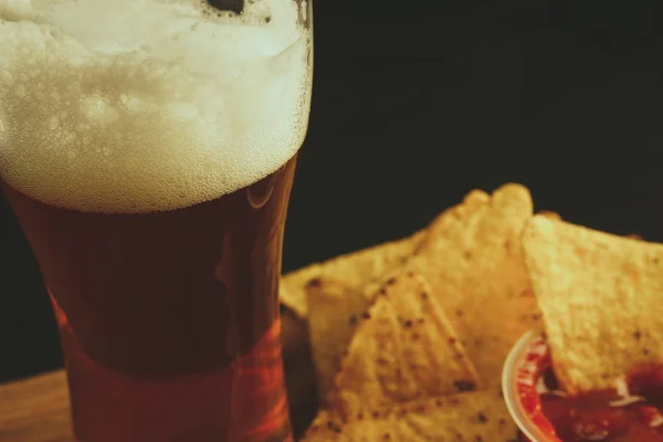 ナチョス チップ添えバック グラウンドで黒の背景にビールのグラス — ストック写真
