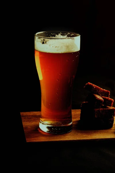 ビールと黒の背景にクルトンのガラス — ストック写真