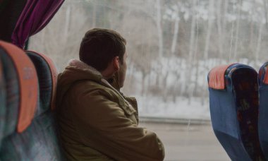 Otobüsle giden sıradan giysili yakışıklı bir genç.