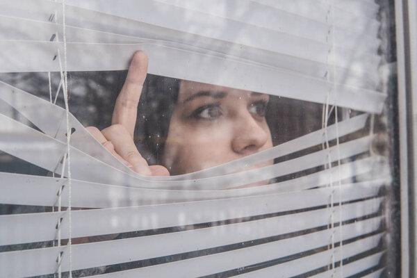 A young girl looking out of blinds
