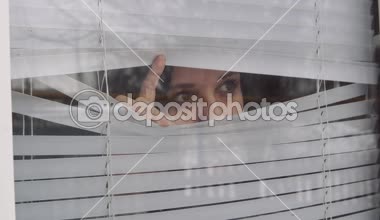 Panjurlardan dışarı bakan genç bir kız.