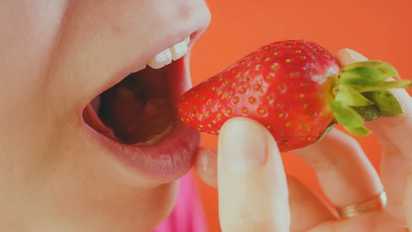 Mulher comendo morangos frescos, close-up. Morangos vermelhos na mão de uma mulher. Conceito: Fruta a chave para uma dieta saudável e figura fina . — Fotografia de Stock