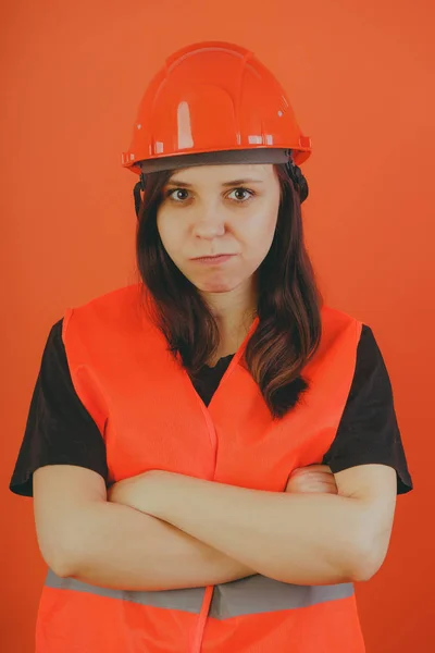 Girl construction worker, road worker or longshoreman, a woman in a helmet and orange vest