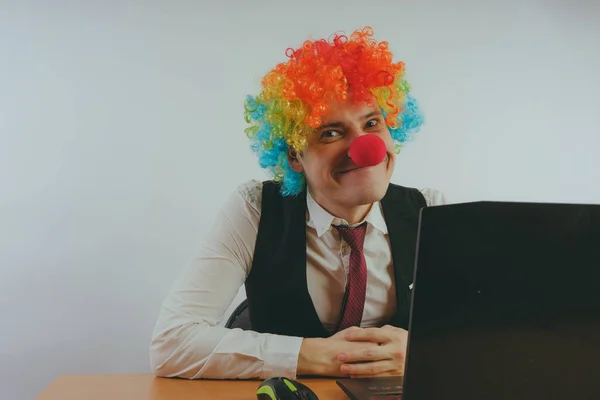 Office worker in clown wig, clown concept at work. Businessman at the computer, work on a laptop
