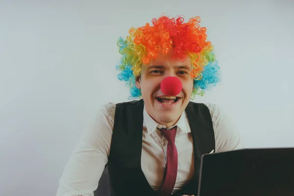 Office worker in clown wig, clown concept at work. Businessman at the computer, work on a laptop