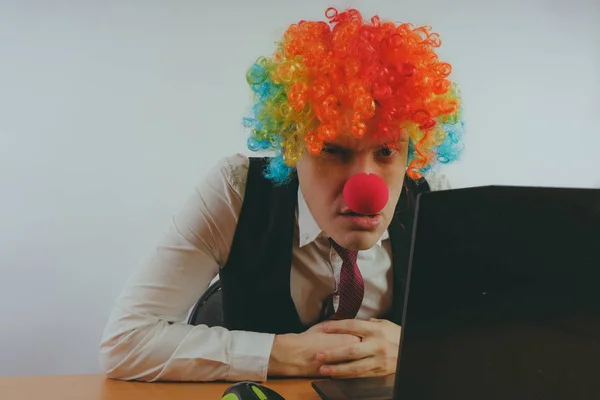 Office worker in clown wig, clown concept at work. Businessman at the computer, work on a laptop