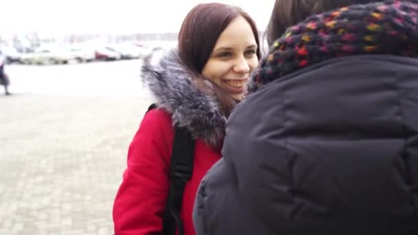 Dos hermosas mujeres paseando por la calle en invierno y charlando bien. Mujeres vestidas de colores cálidos que caminan con un clima frío. — Vídeo de stock