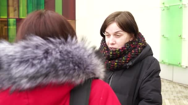 Dos hermosas mujeres paseando por la calle en invierno y charlando bien. Mujeres vestidas de colores cálidos que caminan con un clima frío. — Vídeo de stock