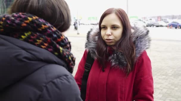 Twee mooie vrouwen die 's winters over straat lopen en een leuk praatje. Vrouwen in warme kleren wandelen in koud weer. — Stockvideo