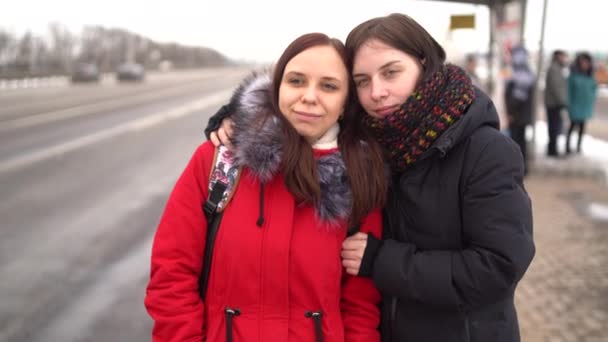 겨울에 아름다운 두 여자가 길을 걷다가 귀여운 채팅을 하고 있습니다. 따뜻 한 옷을 입고 추운 날씨에 걷는 여자들. — 비디오
