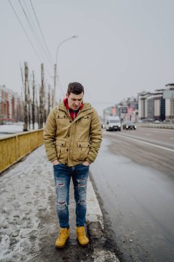 Şehir yolunda günlük giysiler içinde genç yakışıklı bir adam.