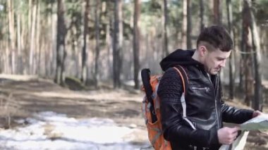 Backpack yürüyüş Travel Lifestyle kavramı ile Traveler Man. Gezgin ormandan geçiyor. Adam ormanda kayboldu ve haritada yolu arıyor.