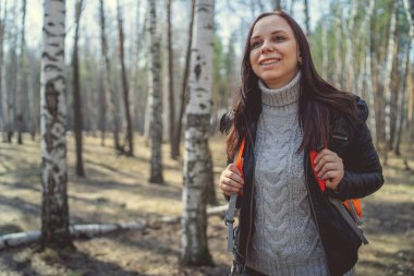Ormanda sırt çantası ile seyahat eden kadın sakin güneşli ormanda parlak turuncu sırt çantası ile duran esmer Yan görünümü uzağa bakan