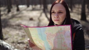 Ormanda harita ile seyahat eden kadın Sırt çantası ile kadının aşağıdan güneş ışığında harita okuma ormanda günlük oturan