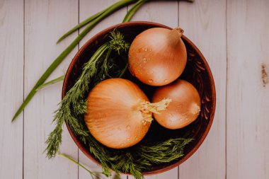 Kasede soğan ve dereotu soğanı. Masaya seramik kaseye yerleştirilen çiğ soğan ve taze yeşil dereotu büyük bütün ampuller