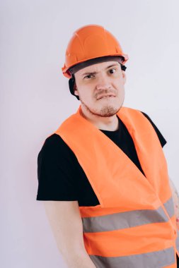 Parlak turuncu koruyucu hardhat ve yelek beyaz arka plan üzerinde kameraya bakarak genç erkek beyaz arka plan üzerinde çalışma üniforması adam