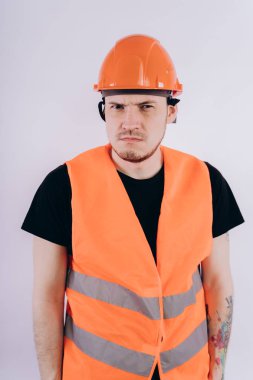 Parlak turuncu koruyucu hardhat ve yelek beyaz arka plan üzerinde kameraya bakarak genç erkek beyaz arka plan üzerinde çalışma üniforması adam