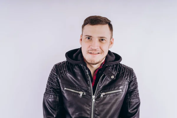 Man in trendy jacket on white backgroundPortrait of young male in leather jacket zipping up and smiling at camera on white background