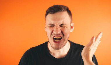 Turuncu arka plana tokat yiyorum mutsuz korkmuş adam turuncu arka planda ayakta tokatlanıyor