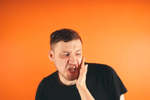 Man getting slapped on orange backgroundUnhappy scared man getting slapped standing on orange background
