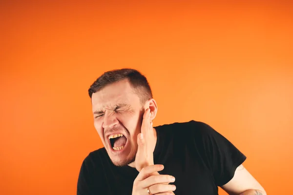 Man getting slapped on orange backgroundUnhappy scared man getting slapped standing on orange background