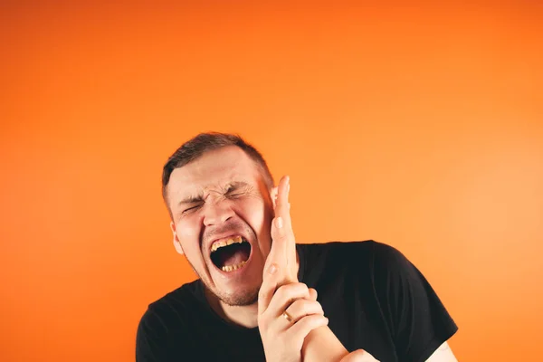 Man getting slapped on orange backgroundUnhappy scared man getting slapped standing on orange background